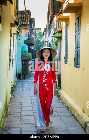 A young Vietnamese woman wearing a traditional Ao Dai dress in the streets of Hoi An, Vietnam Stock Photo