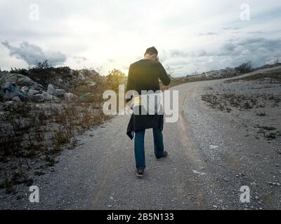 Man goes along the mountain road at sunset Stock Photo