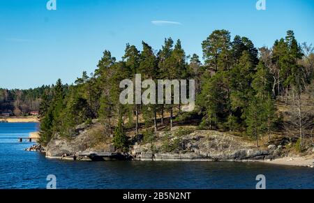 Picturesque summer houses painted in traditional falun red on dwellings island of the Stockholm archipelago in the Baltic Sea in the early morning. Stock Photo
