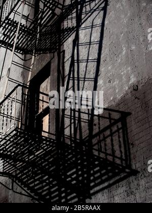 Fire Escape on black building with window and prominent shadows Stock Photo