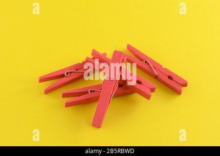 Handful of painted red clothespins on yellow background for crafting projects Stock Photo
