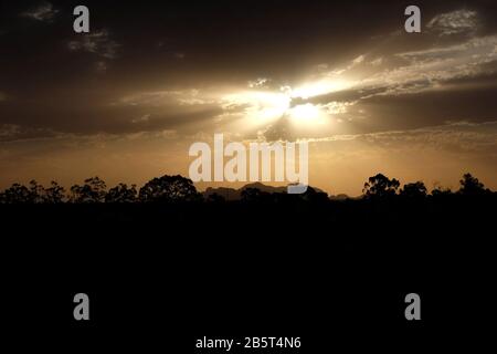 Sunset of Uluru-Kata Tjuta, The Olgas, massive sandstone monoliths and trees in silhouette at dusk the Northern Territory’s "Red Centre" arid desert Stock Photo