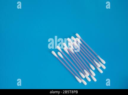 Top view, flat lay, a small group of pink plastic cotton swabs neatly arranged on a blue background, the concept of cleanliness and hygiene. Stock Photo
