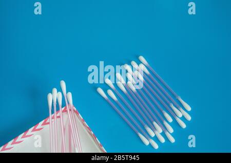 Top view, flat lay, a small group of pink plastic cotton swabs neatly arranged on a blue background, the concept of cleanliness and hygiene. Stock Photo