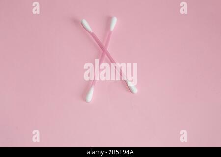 Top view, flat lay, two pink plastic cotton swabs arranged crosswise on a pink background, the concept of cleanliness and hygiene. Stock Photo