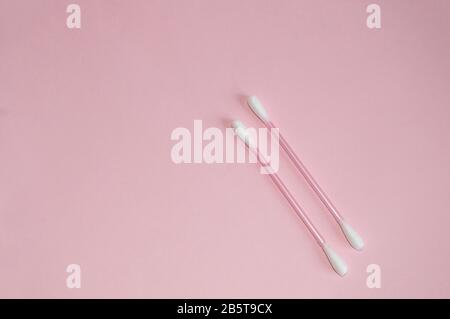 Top view, flat lay, two pink plastic cotton swabs neatly arranged on a pink background, the concept of cleanliness and hygiene. Stock Photo