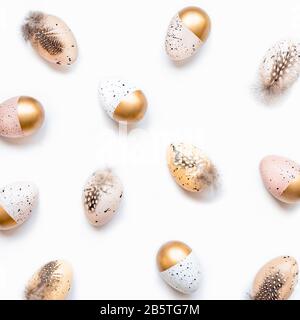 Top view of scattered Easter eggs colored with golden paint in different patterns. White background. Stock Photo