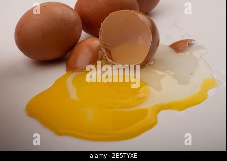 Broken chicken egg and chicken eggs scattered on a white background. Close up Stock Photo