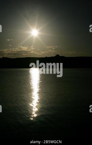 While the sun sets it is reflected on a lake. Stock Photo