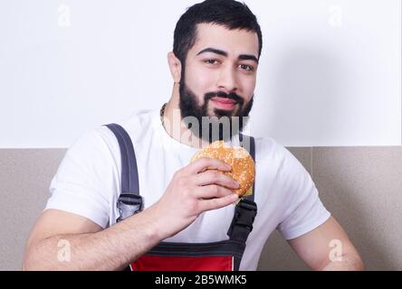 Worker wearing uniform eating burger during lunch break Stock Photo