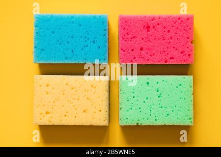 Yellow, green, red, blue sponges on colored paper background, top view. Stock Photo