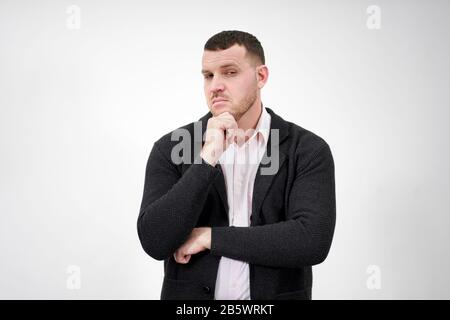 Handsome young pensive man standing against gray background Stock Photo