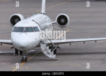 Small passenger airplane parked at the airport with an open door and stairs Stock Photo