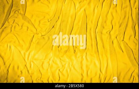 Vibrant yellow texture of binding crumpled fabric. Yellow textile background with natural folds. Close-up Stock Photo