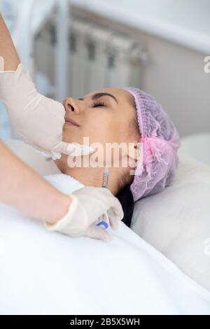 Woman having injection in neck while having anti-aging procedures Stock Photo