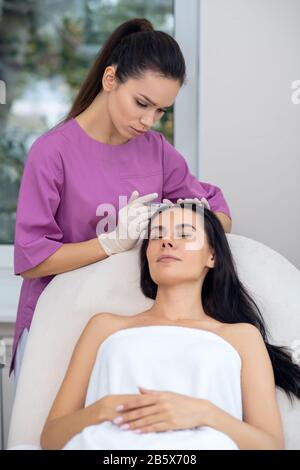 Businesswoman closing eyes while having mesotherapy injection Stock Photo