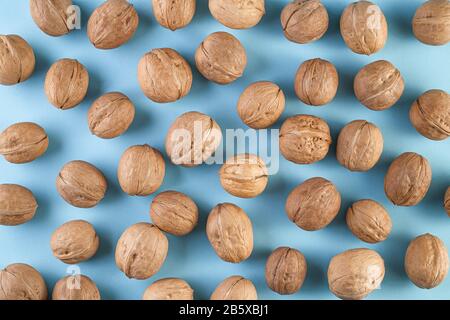 Walnuts on a blue background. Bunch of whole walnuts on a color bright background. Healthy diet composition. Healthy food for brain, vegetarian food. Stock Photo