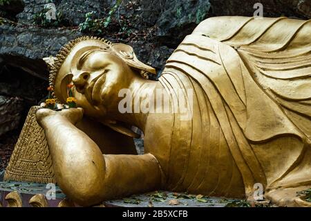 A golden reclining Buddha Statue on Luang Prabang's Phu Si hill at Wat Tham Phu Si Stock Photo