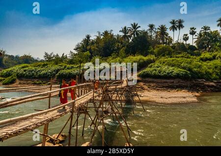 Monks crossing a bamboo bridge over the Nam Khan river in Luang Prabang, Laos.