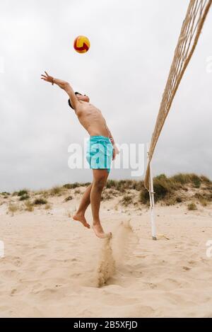 Young man playing volleyball on summer beach. Sport, fitness and people concept Stock Photo