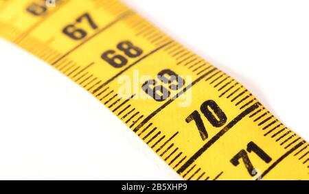 Close-up of a yellow measuring tape isolated on white - 70 - Selective focus Stock Photo