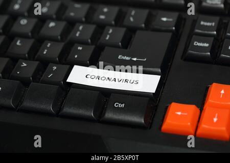 Black computer keyboard with few orange buttons, on one button inscription text CORONAVIRUS. Stock Photo