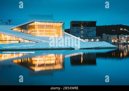 Oslo, Norway. Scenic Night Evening View Of Illuminated Norwegian National Opera And Ballet House Among Contemporary Buildings. Stock Photo