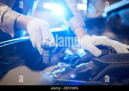 Horizontal close up shot of unrecognizable man's hands in white gloves repairing modern car engine, copy space Stock Photo