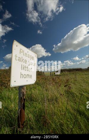 A sign next to a gateway at the side of a road requesting that litter is taken home. England UK GB Stock Photo