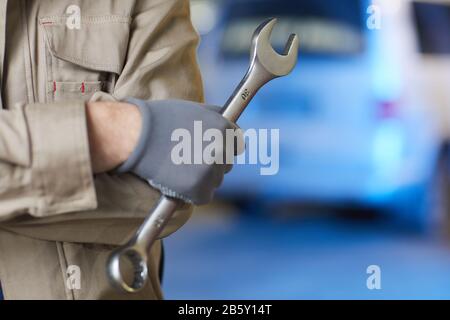 Horizontal close up shot of unrecognizable auto mechanic's hand in glove holding spanner, copy space Stock Photo