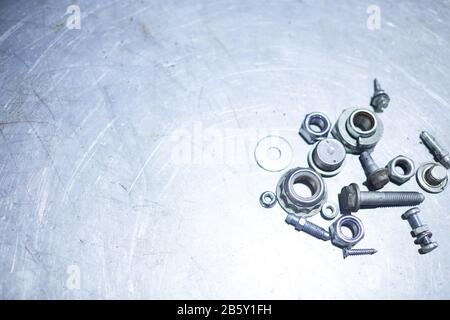 Horizontal high angle flat lay shot of stainless nuts and other details lying on steel surface, copy space Stock Photo