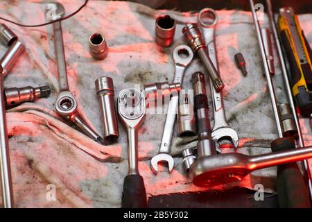 Horizontal high angle flat lay shot of car repair tools on dirty piece of cloth in red light, copy space Stock Photo