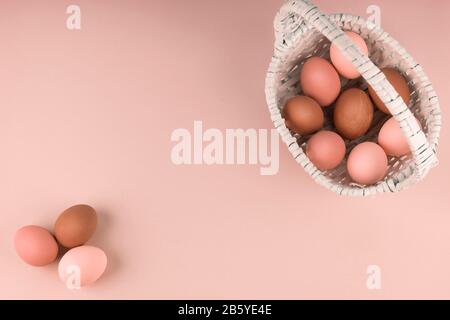 beautiful brown Easter eggs in a basket on a cream background, copyspace, warm uniform color. Stock Photo