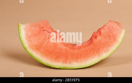 One slice of watermelon with big bite on beige studio background Stock Photo
