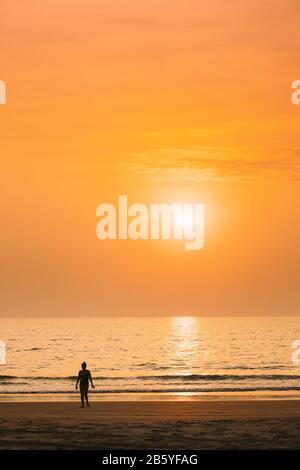 Dark Silhouette Of Young Caucasian Lady Woman In Swimsuit Walking In Sea Beach During Sunset. Vacation On Ocean Beach. Sundown Above Sea Horizon At Su