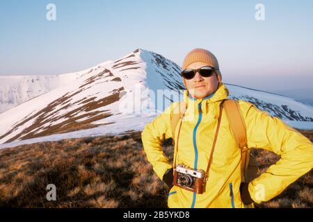 Photographer in yellow jacket taking photo on snowy winter field Stock Photo