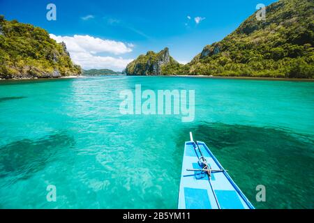 Trip tourist boat in blue shallow water lagoon. Discover exploring unique nature, journey to paradise approaching tropical island. Stock Photo