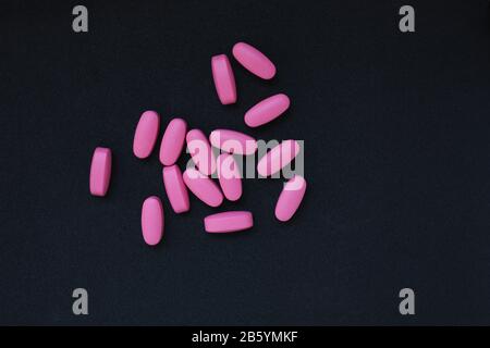 Pink pills on dark background with copy space. The concept of healthcare. Flatlay, top view, copyspace for text. Stock Photo