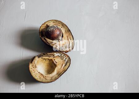 Halves of rotten spoiled avocado fruit and seeds on a gray background. Close-up. Copy space. Stop wasting food concepts, food poisoning, eating stale Stock Photo