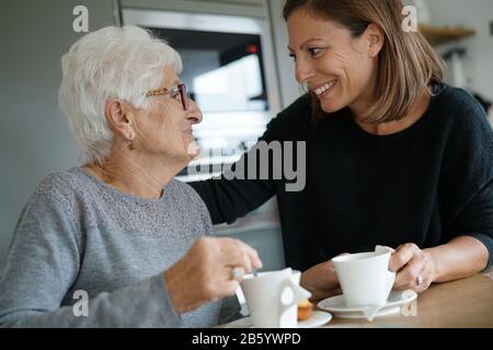 Homecarer serving tea to elderly woman Stock Photo