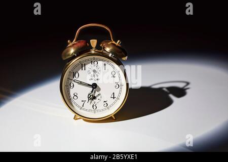 Old fashioned mechanical alarm clock with bells on top with hands at twelve minutes to seven Stock Photo