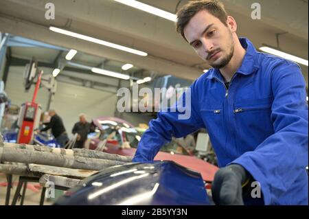 Apprentice working on car engine in workshop Stock Photo