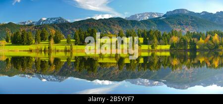panoramic landscape with meadow and lake in front of alps mountains Stock Photo