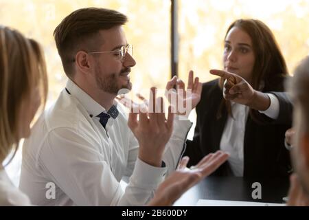 Young stress resistant employee calming down while colleagues blaming him. Stock Photo