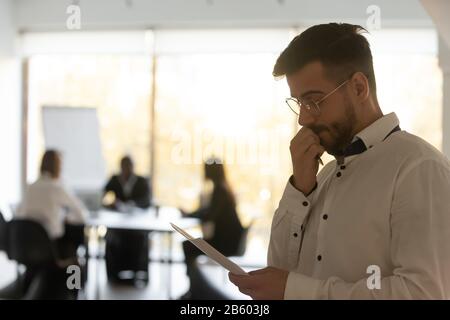 Side view concentrated millennial male businessman holding document. Stock Photo