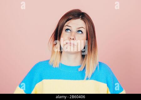 young fresh - looking woman with interrogative questioning thinking expression looking above Stock Photo