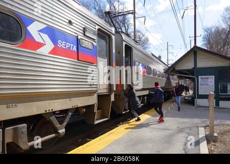 People boarding a SEPTA Chestnut Hill West Line commuter train at Upsal station in Northwest Philly, Philadelphia, PA. February 29, 2020 Stock Photo