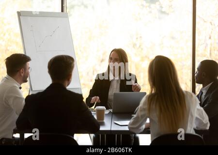 Confident smiling female team leader discussing new project with colleagues. Stock Photo