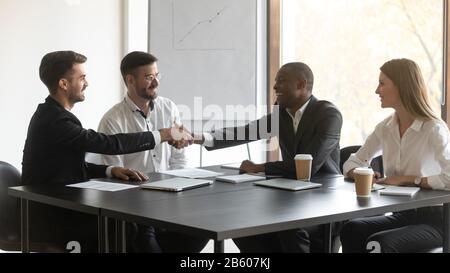 Happy mixed race millennial company representatives shaking hands with partners. Stock Photo
