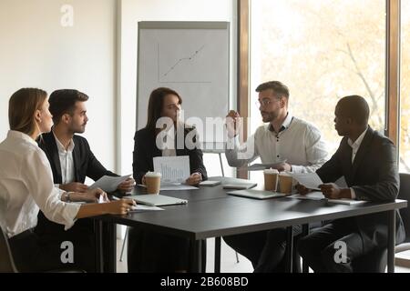 Mixed race young business employees team listening to leader. Stock Photo